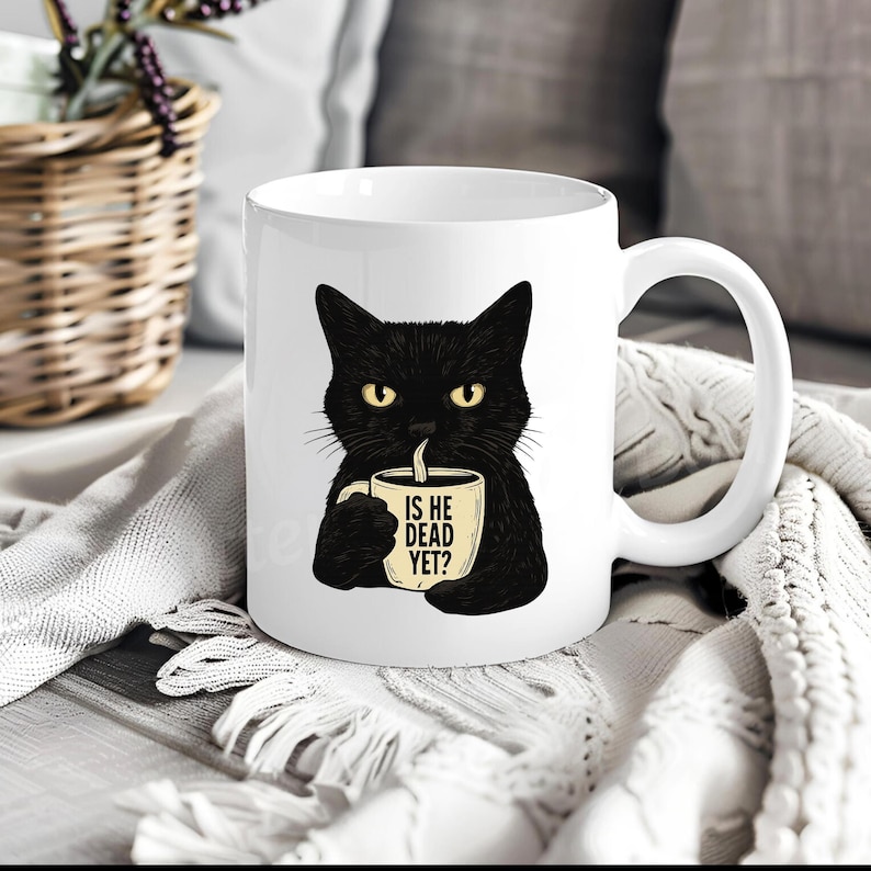 May include: White ceramic mug featuring a black cat with yellow eyes, holding a coffee cup. The cup has the text "IS HE DEAD YET?" in black. The mug has a white handle and is set against a soft, textured background.