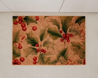 May include: Rectangular doormat featuring a festive holly and berry design. The mat has a speckled tan background with green holly leaves and clusters of red berries. The border is a light beige.