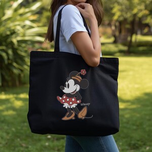 May include: Black tote bag with a Minnie Mouse design. The cartoon mouse is wearing a red polka dot dress, brown shoes, and a hat with a flower. The Disney logo is printed on the bag.