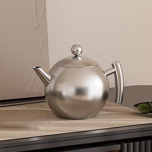 Può includere: Una teiera in acciaio inossidabile con corpo sferico, un piccolo beccuccio e un manico curvo. Il coperchio è sormontato da un piccolo pomello rotondo. La teiera è appoggiata su una superficie colorata neutra.