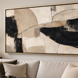 Puede incluir: Una pintura abstracta rectangular grande en un marco dorado con pinceladas audaces en negro, beige y crema. La composición incluye líneas curvas y aplicaciones de pintura texturizada que crean un efecto visual de alto contraste.