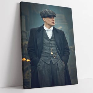 Op de afbeelding: Een canvas print met een man in een grijs tweed pak, zwarte overjas en een grijze pet, die een sigaret rookt. Een gouden zakhorloge hangt aan zijn vest. De achtergrond is een vage, rokerige scène.
