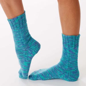 Pode incluir: Um par de meias de malha azul e verde-azulado. As meias têm uma bainha canelada e um padrão salpicado. São exibidas sobre um fundo branco.