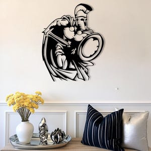 Könnte beinhalten: Schwarze Metall-Wandkunst, die einen spartanischen Krieger in dynamischer Pose mit Schwert und Schild darstellt. Das Kunstwerk zeigt detaillierte Elemente der Rüstung und des Umhangs des Kriegers und bildet eine markante Silhouette. An einer weißen Wand montiert.
