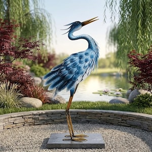 Può includere: Una scultura da giardino in metallo raffigurante un airone blu su una base quadrata in pietra. L'uccello presenta piume stratificate blu e bianche, un lungo collo ricurvo e un becco giallo appuntito rivolto verso l'alto con bocca aperta.