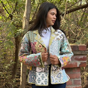 May include: A patchwork jacket with a variety of floral and geometric patterns in shades of pink, blue, green, and yellow. The jacket has a tailored fit with a notched collar and button closure. The jacket is a unique piece of clothing.