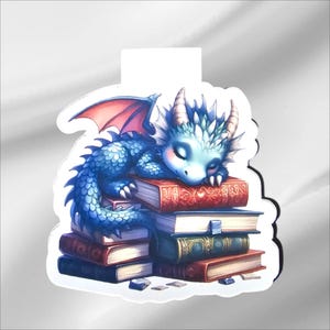 Peut inclure: Autocollant représentant un dragon bleu endormi avec des accents roses, reposant sur une pile de livres. Le dragon a les yeux fermés et de petites cornes. Les livres sont de couleurs variées, dont le rouge, le vert et le marron.