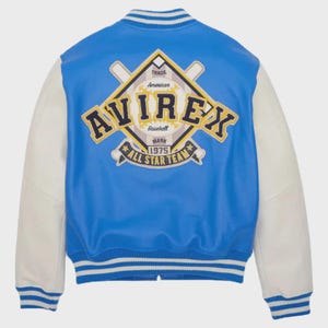 Op de afbeelding: Blauw-witte baseballjack met het "AVIREX" logo en de tekst "ALL STAR TEAM" op de rug. De jas heeft witte mouwen en een blauwe body. Het heeft een geribbelde kraag, manchetten en zoom met witte strepen.
