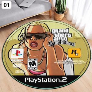 Può includere: Un tappeto circolare con la copertina del videogioco Grand Theft Auto San Andreas. Il design include un personaggio biondo con occhiali da sole, il titolo del gioco, il marchio PlayStation 2, una classificazione ESRB Mature 17+ e testi di copyright.