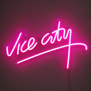 Peut inclure: Une enseigne néon rose vif affichant les mots vice city dans une écriture cursive fluide et continue. Le tube lumineux forme les lettres avec un éclat vibrant, incluant un long soulignement horizontal partant de la lettre y.