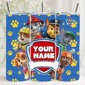 Op de afbeelding: Een blauwe beker met de Paw Patrol-personages en de tekst "YOUR NAME" in een rood-wit schild. Het ontwerp bevat gele pootafdrukken en het Paw Patrol-logo.