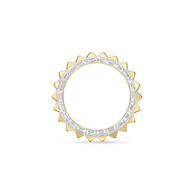 May include: A gold ring with a sunburst design. The ring features a band of rectangular, clear stones set within a gold frame. The outer edge of the ring has a series of triangular gold points, creating a sun-like appearance.