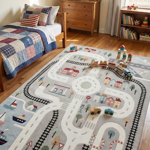 May include: A gray road and train track rug with a town scene. The rug features roads, train tracks, buildings, trees, and a boat. Wooden toy cars and trains are placed on the rug.