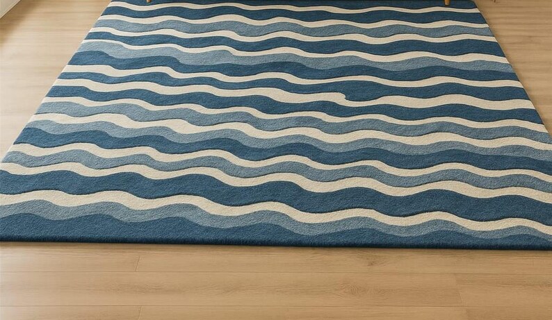 Pu&ograve; includere: Un tappeto rettangolare con un motivo a onde in tonalit&agrave; di blu e bianco sporco. Il design del tappeto ricorda le onde dell'oceano, creando un'estetica rilassante e visivamente accattivante. Il tappeto &egrave; posizionato su un pavimento in legno chiaro.