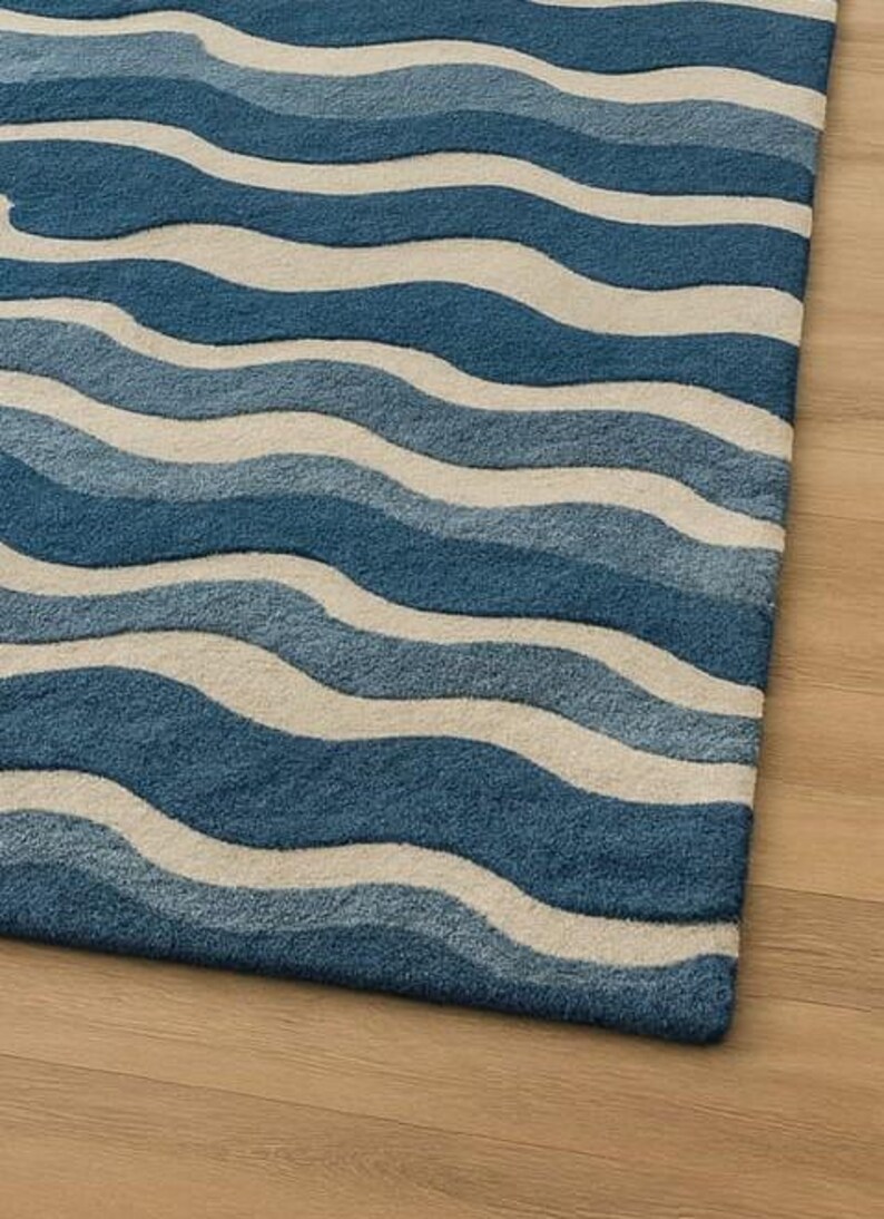 Pu&ograve; includere: Un tappeto blu e bianco con un motivo a onde. Il tappeto presenta fasce alternate di diverse tonalit&agrave; di blu e bianco sporco, creando un motivo strutturato simile all'oceano. Il tappeto &egrave; realizzato in un materiale morbido ed &egrave; adatto per un soggiorno o una camera da letto.