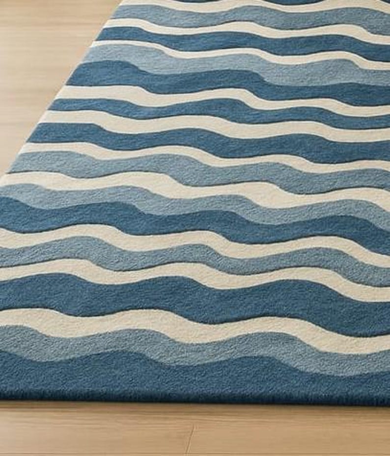 Pu&ograve; includere: Tappeto blu e bianco con motivo a onde. Il tappeto presenta fasce alternate di diverse tonalit&agrave; di blu e bianco, creando un design strutturato che evoca l'oceano. Il tappeto &egrave; realizzato in materiale morbido ed &egrave; adatto per uso interno.