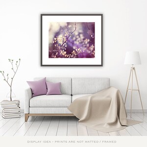 Pu&ograve; includere: Una stampa artistica incorniciata con un primo piano di fogliame viola. L'opera d'arte &egrave; sopra un divano grigio chiaro con due cuscini lavanda e una coperta beige. Una moderna lampada da terra e una pianta decorativa completano la stanza.