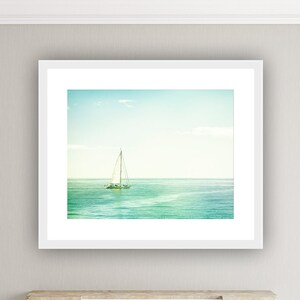 May include: A white framed photograph of a sailboat on a calm, blue ocean. The photo is displayed above a white fireplace mantel with four white candles.