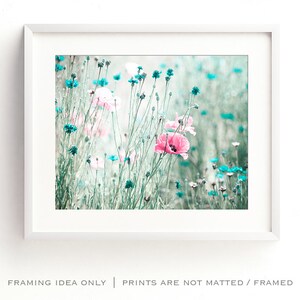Pode incluir: Uma impress&atilde;o emoldurada com um campo de papoilas cor-de-rosa e flores silvestres turquesas. A imagem tem uma qualidade suave e sonhadora, com um fundo desfocado. A moldura branca envolve a obra de arte, que &eacute; uma impress&atilde;o com tema natural.