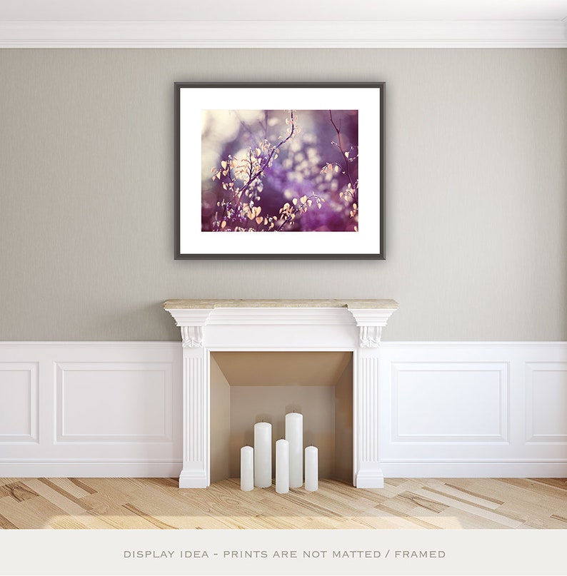 Pu&ograve; includere: Una stampa artistica incorniciata con un primo piano di una pianta con piccole foglie chiare e fiori viola e bianchi. L'opera d'arte &egrave; esposta sopra un camino bianco con cinque candele bianche. La stanza ha pareti di colore chiaro e un pavimento in legno.