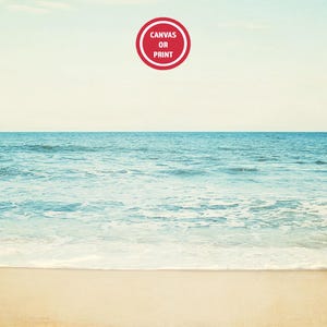 Może przedstawiać: Spokojna scena na plaży z jasnoniebieskim oceanem spotykającym piaszczystą plażę pod bladym niebem. Czerwony okrągły graficzny element w g&oacute;rnej części środkowej części zawiera napis "Canvas or Print". Obraz wywołuje poczucie spokoju i naturalnego piękna.