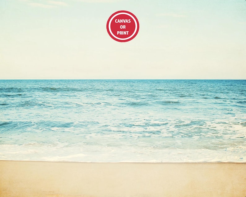 Może przedstawiać: Spokojna scena na plaży z jasnoniebieskim oceanem spotykającym piaszczystą plażę pod bladym niebem. Czerwony okrągły graficzny element w g&oacute;rnej części środkowej części zawiera napis "Canvas or Print". Obraz wywołuje poczucie spokoju i naturalnego piękna.