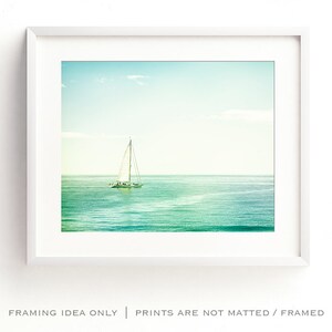May include: A framed print of a sailboat on the ocean. The image features a white sailboat with its sails up, sailing on turquoise water under a light blue sky. The frame is white, and the text at the bottom reads "FRAMING IDEA ONLY | PRINTS ARE NOT MATTED / FRAMED."