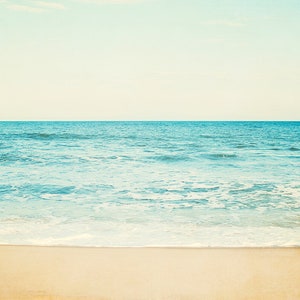 A tranquil beach seascape with a light sky, blue ocean water, and a sandy shore.  Available as a Fine Art Print or Canvas Gallery Wrap.