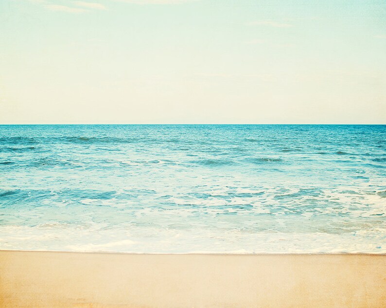 A tranquil beach seascape with a light sky, blue ocean water, and a sandy shore.  Available as a Fine Art Print or Canvas Gallery Wrap.