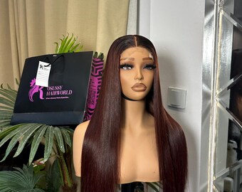 May include: A mannequin head with a long, straight, burgundy wig. The wig is styled with a natural hairline. A black shopping bag with the text "OSUSSY HAIRWORLD" is visible in the background.