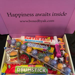 May include: A box filled with various candies, including a Drumstick bar, Love Hearts, and Refreshers. The box lid reads "Happiness awaits inside" with a website address. Colorful sweets are arranged inside.