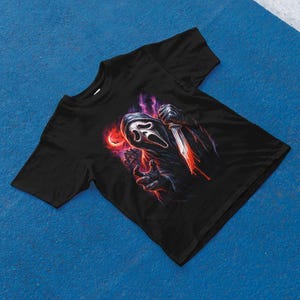 Pu&ograve; includere: T-shirt nero con una grafica dell'assassino Ghostface del franchise di Scream. Il design mostra Ghostface che tiene un coltello insanguinato su uno sfondo rosso e viola. La maglietta &egrave; realizzata in un materiale morbido.