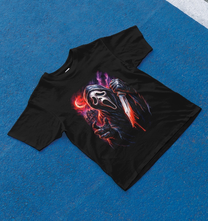 Pu&ograve; includere: T-shirt nero con una grafica dell'assassino Ghostface del franchise di Scream. Il design mostra Ghostface che tiene un coltello insanguinato su uno sfondo rosso e viola. La maglietta &egrave; realizzata in un materiale morbido.