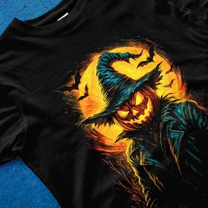 Pu&ograve; includere: T-shirt nero con un'illustrazione a tema Halloween. Il design presenta una zucca con un cappello da strega sullo sfondo di una luna piena e pipistrelli. L'opera d'arte utilizza una vivace tavolozza di colori arancione, giallo e verde acqua.