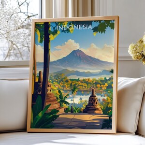 May include: A framed art print showcasing an Indonesian landscape. The image displays a mountain, lake, temples, and vibrant foliage. The word "INDONESIA" is visible. The frame is a light brown colour.