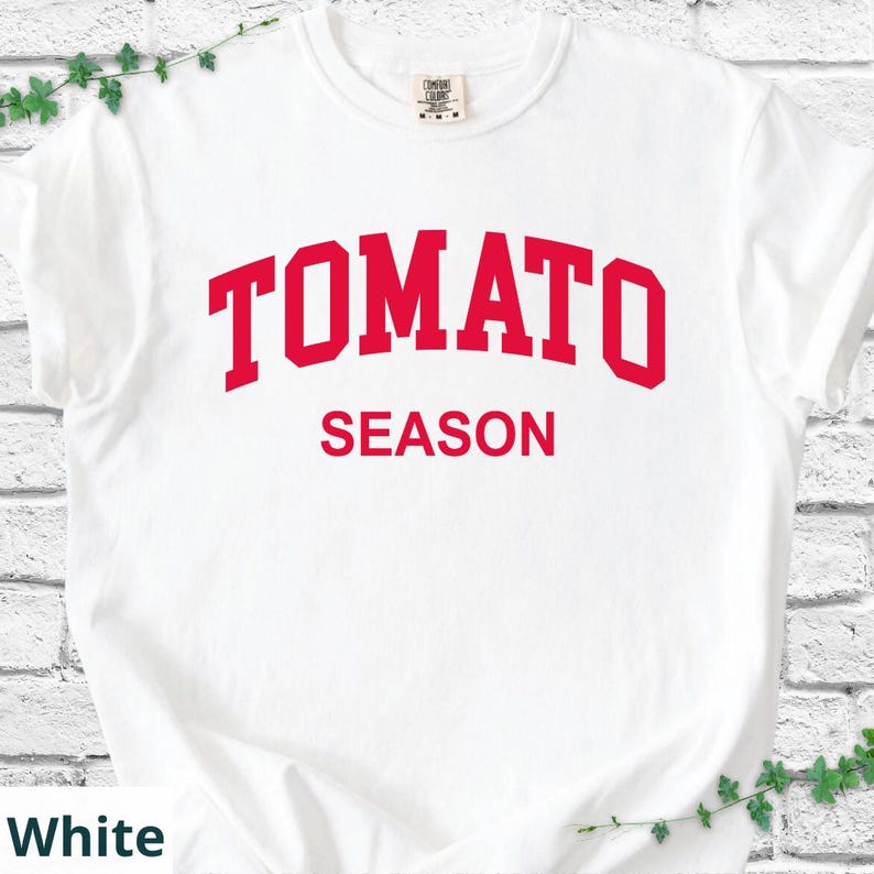 K&ouml;nnte beinhalten: Wei&szlig;es T-Shirt mit dem Text "TOMATO SEASON" in roten, fetten Buchstaben. Der Text ist oben auf dem T-Shirt gebogen. Das Shirt hat einen Rundhalsausschnitt und ist aus weichem Material.