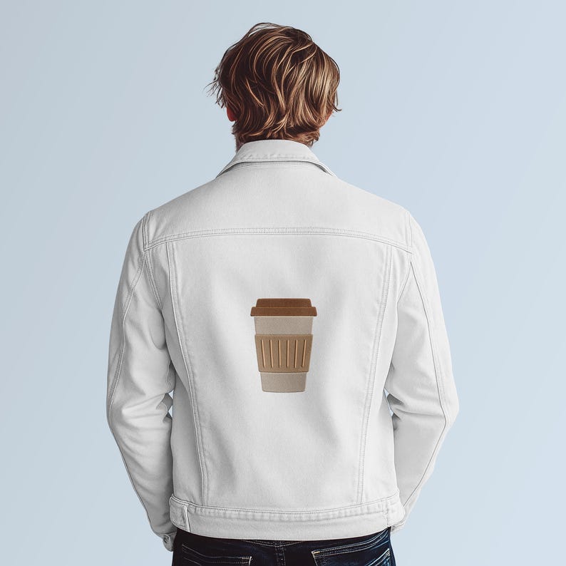Puede incluir: Chaqueta vaquera blanca con un gr&aacute;fico de taza de caf&eacute; en la espalda. La taza de caf&eacute; tiene una tapa marr&oacute;n y una manga beige. La chaqueta tiene un cuello cl&aacute;sico, cierre de botones y dos bolsillos en el pecho.