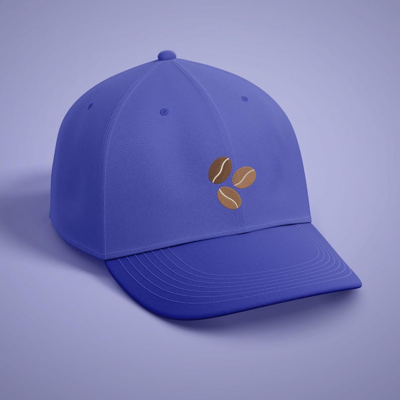 Puede incluir: Gorra de b&eacute;isbol azul con tres granos de caf&eacute; bordados en tonos marrones. La gorra tiene una visera curva y un bot&oacute;n en la parte superior. El sombrero es de color azul liso.