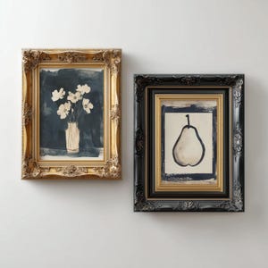 May include: Two framed art prints. One shows white flowers in a vase against a dark blue backdrop, in a gold frame. The other print features a pear illustration in a black and gold frame.