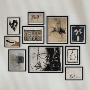 May include: A collection of framed art prints in various sizes and styles. The artwork includes abstract designs, a bull, a building facade, a pear, and a bicycle. The frames are black, and the art pieces are in black, white, and neutral tones.
