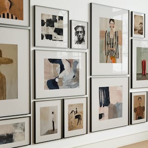 Pode incluir: Uma coleção de impressões de arte emolduradas em vários tamanhos e estilos, incluindo pinturas abstratas, retratos e arte figurativa. As molduras são pretas e a arte apresenta uma paleta de cores neutras com toques de cor.