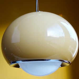 May include: A modern, spherical pendant light fixture. The light has a glossy, cream-colored globe with a chrome-colored trim and a white, rounded bottom. The light hangs from a thin, silver-colored wire.
