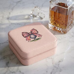 Estuche de viaje para joyas con lazo y diseño floral, organizador compacto con ranuras para anillos.