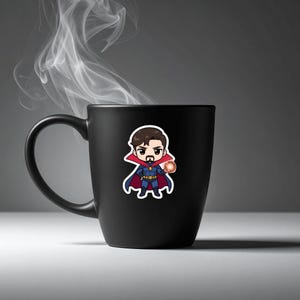 May include: A black ceramic mug with a cartoon sticker of Doctor Strange. The sticker depicts the character in a blue and red costume, holding an orange energy ball. Wisps of white steam rise from the mug.