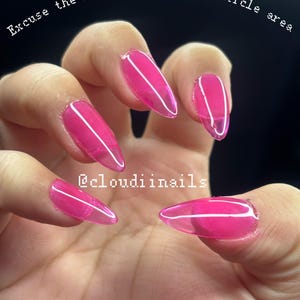 May include: A hand displaying five long, oval-shaped, bright pink gel nails. The nails have a translucent appearance with a white line design. Text at the top reads "Excuse the latex glue around cuticle area" and the bottom reads "@cloudiinnails".