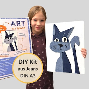 Könnte beinhalten: Ein junges Mädchen hält ein DIY-Kunst-Kit und ein fertiges Kunstwerk. Das Kunstwerk ist eine Katze aus Jeansstoff. Auf der Kit-Box steht "ART the TRASH" und "DIY Kit aus Jeans DIN A3". Das Kunstwerk befindet sich auf einer weißen Leinwand.