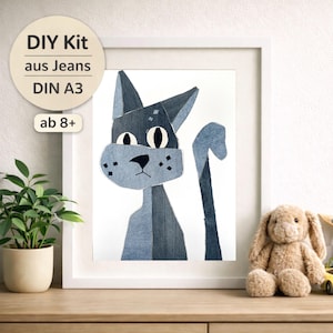 Könnte beinhalten: Gerahmte Illustration einer Katze aus Jeansstoff. Die Katze ist in verschiedenen Blautönen dargestellt, vor einem weißen Hintergrund in einem weißen Rahmen. Der Text auf dem Bild lautet "DIY Kit aus Jeans DIN A3 ab 8+", für Kinder ab 8 Jahren.