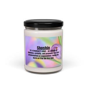 Könnte beinhalten: Ein weißes Kerzenglas mit schwarzem Deckel. Das Etikett zeigt das Wort "Shoshin" und seine Definition sowie eine lila Blumengrafik. Der Hintergrund hat ein farbenfrohes, schillerndes Design. Die Kerze ist ein Einrichtungsgegenstand.