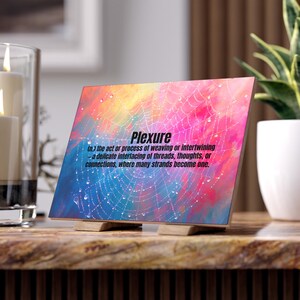 May include: A decorative wooden plaque with the word "Plexure" in bold, black font. The background features a colorful abstract design with a web-like pattern and water droplets. The definition of Plexure is also included.