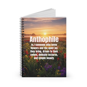 May include: A spiral-bound notebook with the word "Anthophile" in white text. The cover features a sunrise over a field of colorful wildflowers. The definition of "Anthophile" is also printed on the cover.